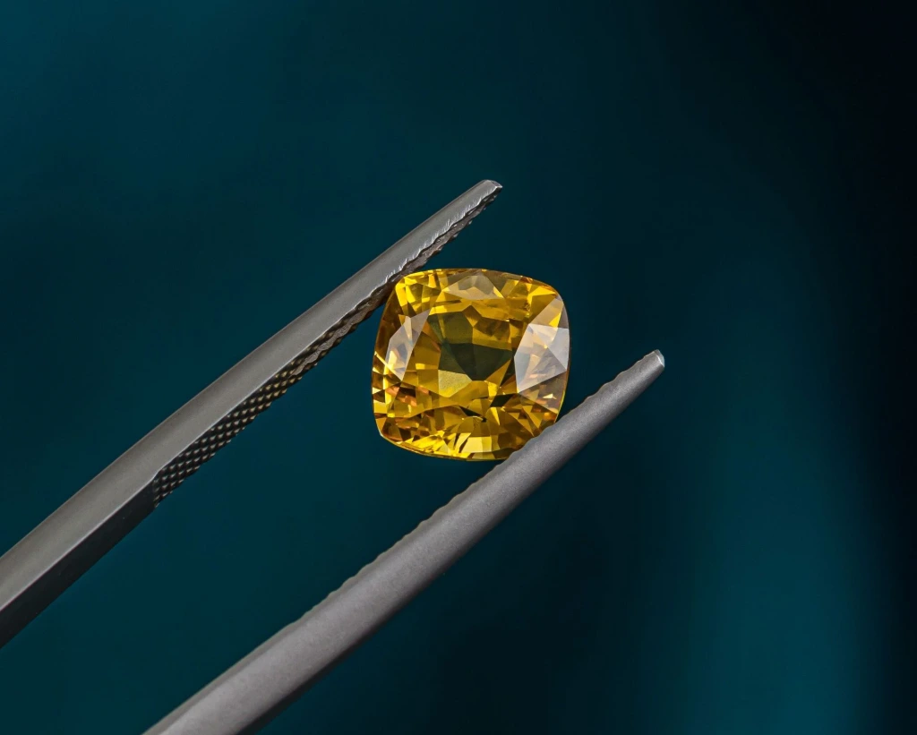 A fine yellow sapphire in tweezers